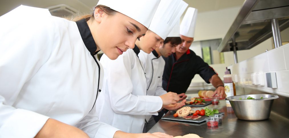 Dieses Foto zeigt Auszubildende in der Küche, die ihre Fähigkeiten im Bereich der Gastronomie und des Kochens verbessern. Eine Karriere in der Gastronomie erfordert ein hohes Maß an Kreativität, Leidenschaft und Fähigkeiten, um den Gästen eine einzigartige kulinarische Erfahrung zu bieten. Wenn Sie eine Karriere in der Gastronomie anstreben, gibt es viele Ausbildungsmöglichkeiten im Tourismus, die Ihnen helfen können, Ihre Fähigkeiten und Kenntnisse in diesem Bereich zu verbessern.