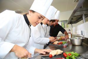 Dieses Foto zeigt Auszubildende in der Küche, die ihre Fähigkeiten im Bereich der Gastronomie und des Kochens verbessern. Eine Karriere in der Gastronomie erfordert ein hohes Maß an Kreativität, Leidenschaft und Fähigkeiten, um den Gästen eine einzigartige kulinarische Erfahrung zu bieten. Wenn Sie eine Karriere in der Gastronomie anstreben, gibt es viele Ausbildungsmöglichkeiten im Tourismus, die Ihnen helfen können, Ihre Fähigkeiten und Kenntnisse in diesem Bereich zu verbessern.